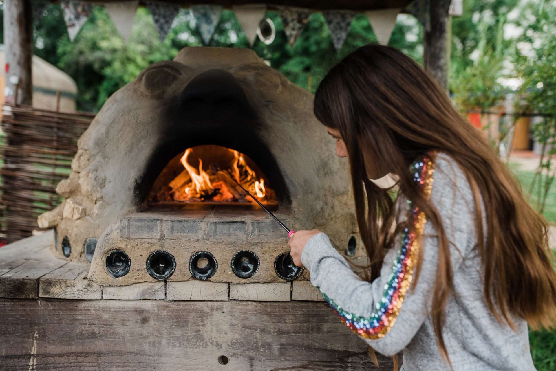 Flames inside the cob pizza oven and girl toasting marshmallows